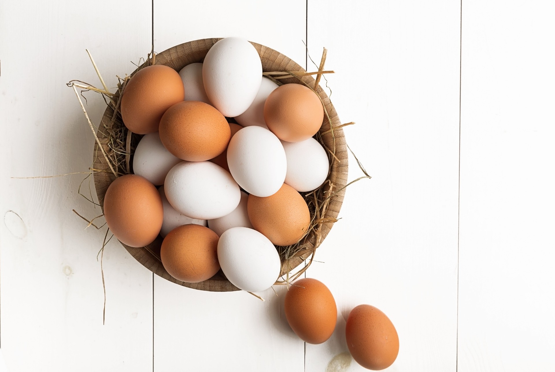 Eggs in box container on a white wooden table. Top view